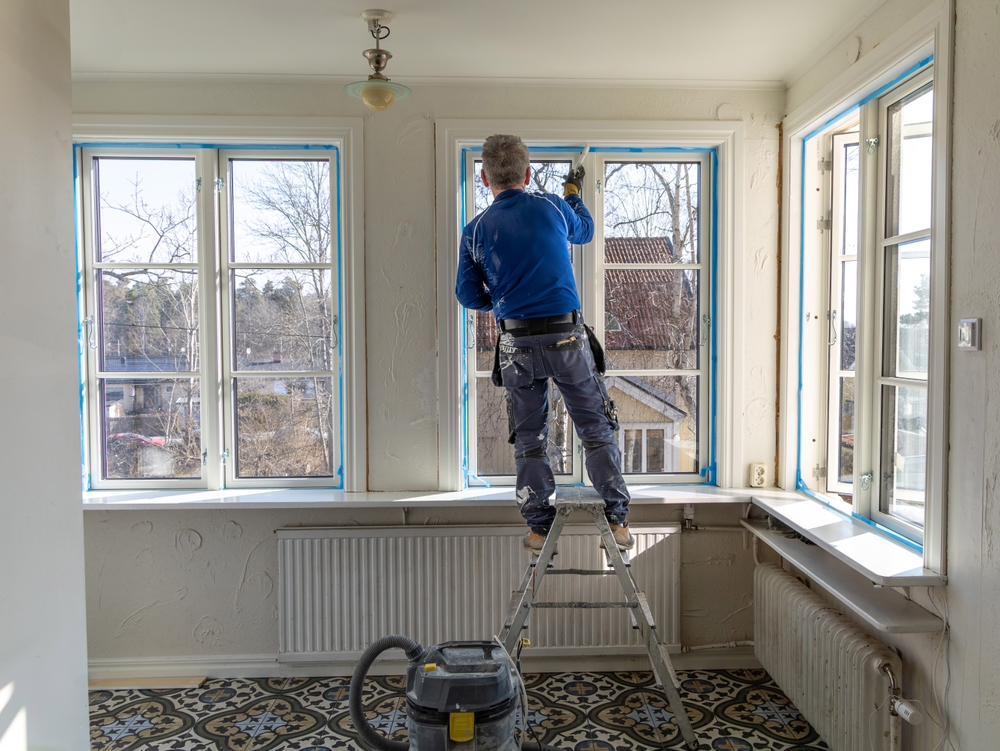 A,Professional,Painter,Standing,On,A,Ladder,Paints,The,Trim